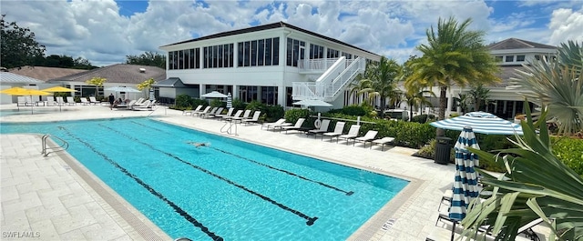 view of swimming pool with a sunroom and a patio area