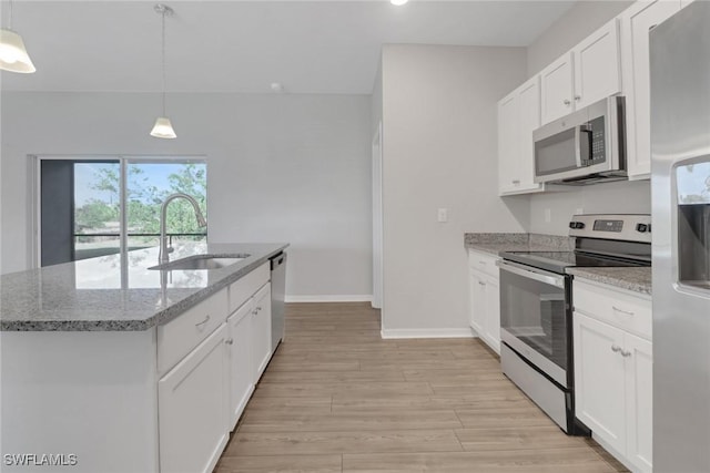 kitchen with sink, hanging light fixtures, an island with sink, stainless steel appliances, and white cabinets