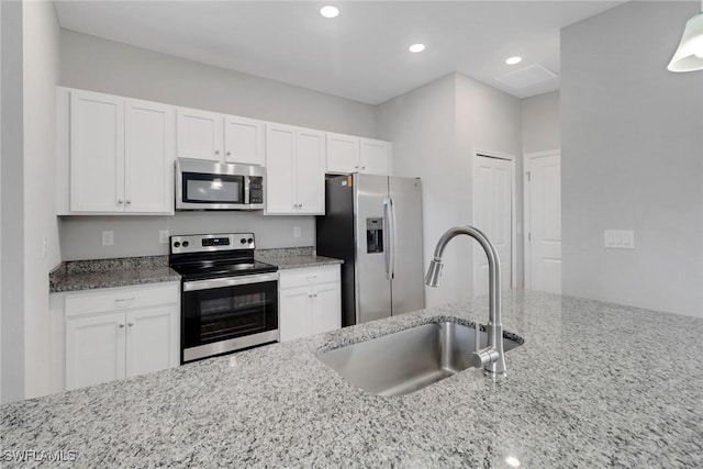 kitchen with white cabinetry, appliances with stainless steel finishes, sink, and light stone counters