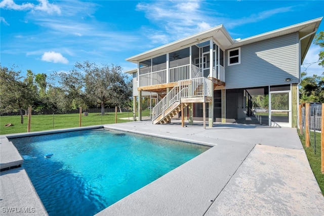 view of swimming pool featuring a patio area, a sunroom, and a lawn