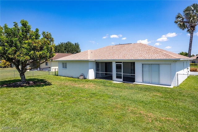 rear view of house with a lawn and a sunroom