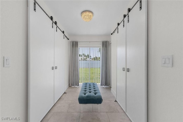 hall with light tile patterned flooring and a barn door