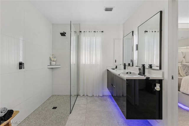 bathroom with tile patterned flooring, vanity, and tiled shower