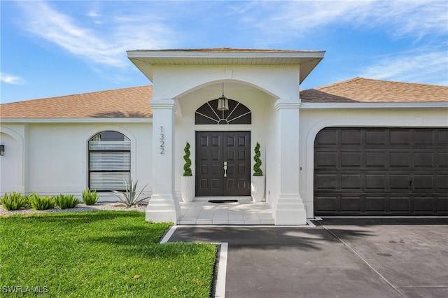 view of exterior entry featuring a garage and a yard