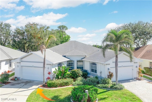 view of front of house with a garage, driveway, roof with shingles, stucco siding, and a front yard