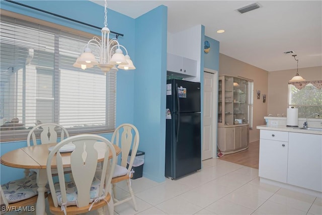 kitchen featuring pendant lighting, freestanding refrigerator, white cabinets, and visible vents