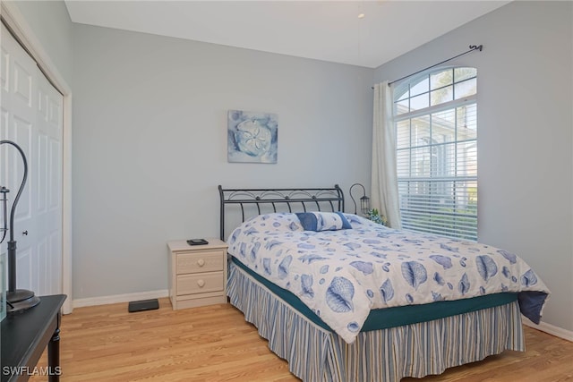 bedroom with light wood-style floors, a closet, and baseboards