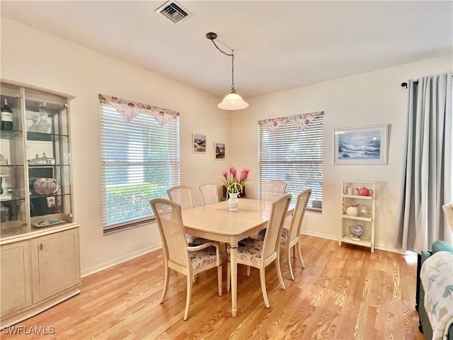 dining area with light wood-style floors, visible vents, and baseboards