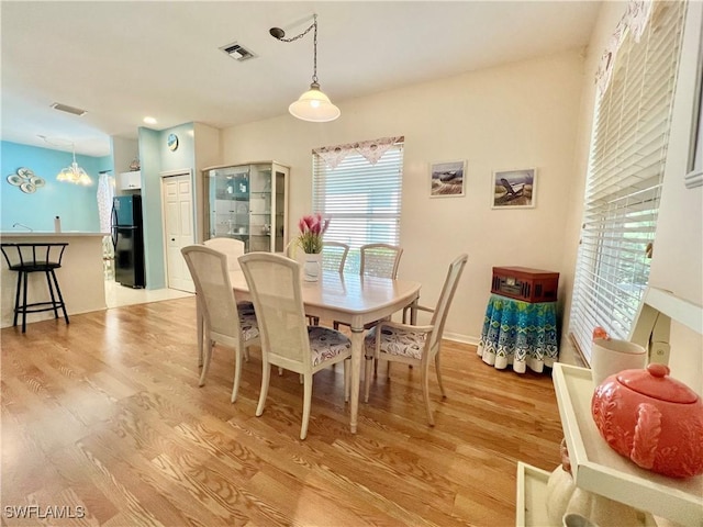 dining space featuring light wood-type flooring and visible vents