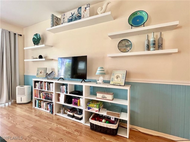 sitting room featuring a wainscoted wall and wood finished floors