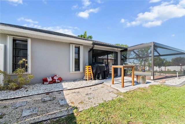 exterior space featuring a patio, glass enclosure, and a lawn