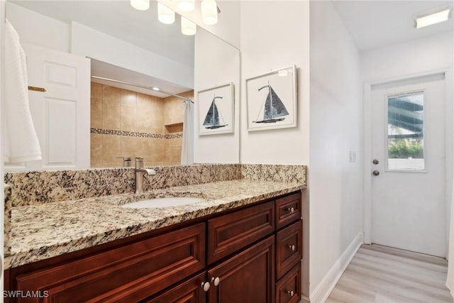 bathroom with walk in shower, vanity, and hardwood / wood-style floors