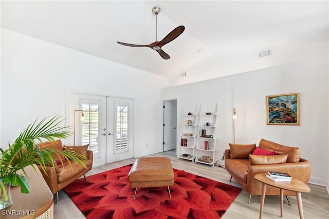 living room with french doors, light hardwood / wood-style floors, and vaulted ceiling