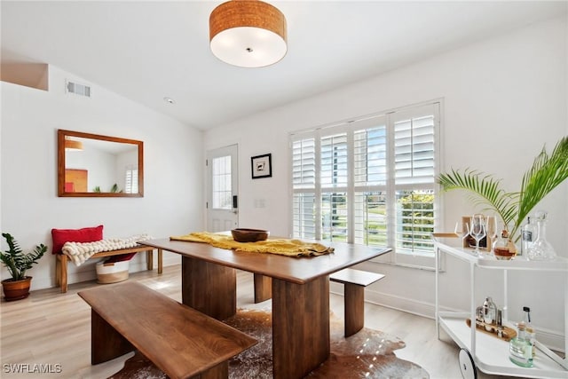 dining room with breakfast area, a wealth of natural light, vaulted ceiling, and light hardwood / wood-style flooring