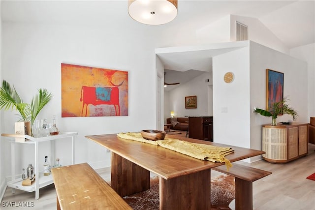 dining space with high vaulted ceiling and light hardwood / wood-style floors