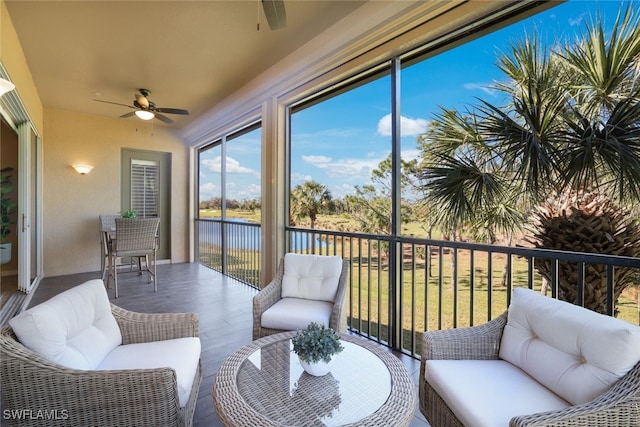 sunroom with ceiling fan and a water view