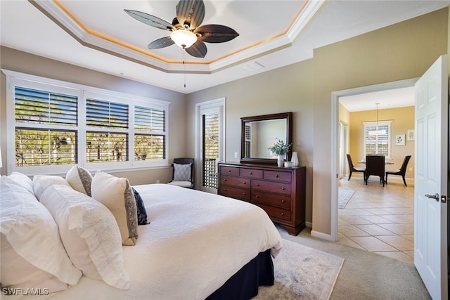 bedroom with ceiling fan, ornamental molding, a tray ceiling, and light tile patterned floors