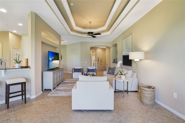 living room with crown molding, ceiling fan, a tray ceiling, and light tile patterned flooring