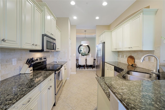 kitchen featuring appliances with stainless steel finishes, sink, white cabinets, dark stone counters, and hanging light fixtures