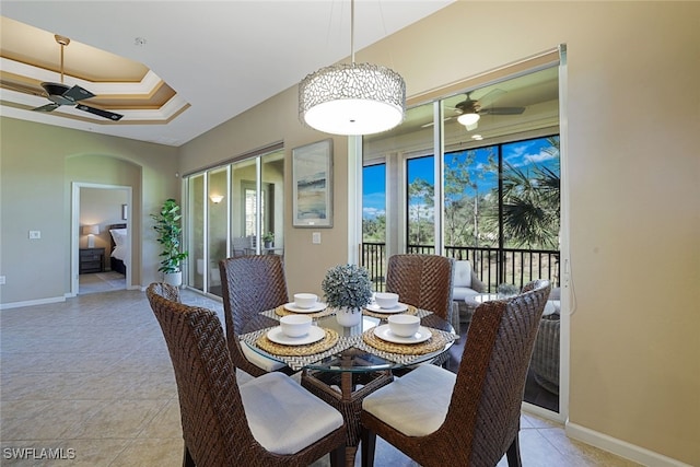 tiled dining space featuring ceiling fan and a tray ceiling