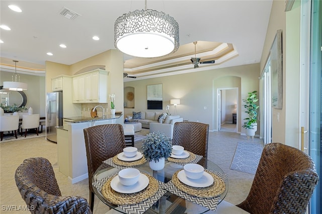 dining space with crown molding, a raised ceiling, sink, and light tile patterned floors