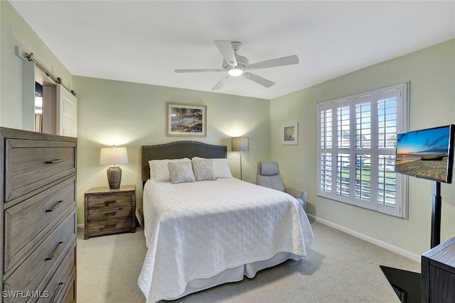 bedroom featuring a barn door, light carpet, and ceiling fan