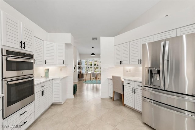 kitchen with white cabinetry, lofted ceiling, decorative backsplash, hanging light fixtures, and stainless steel appliances