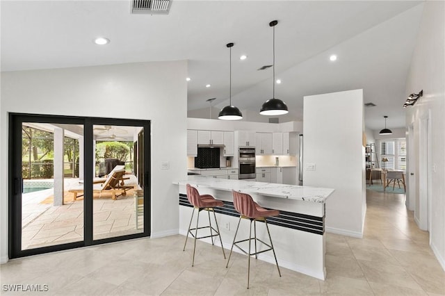 kitchen featuring white cabinets, a kitchen breakfast bar, hanging light fixtures, kitchen peninsula, and light stone countertops