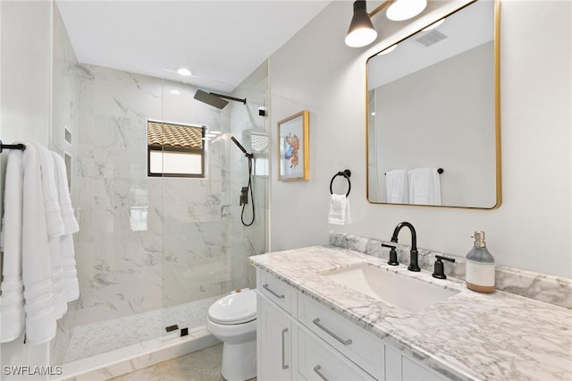 bathroom with vanity, toilet, and a tile shower