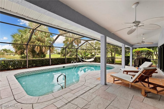 view of swimming pool with ceiling fan, glass enclosure, and a patio area