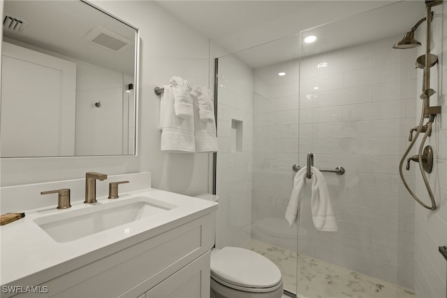 bathroom with tiled shower, vanity, and toilet