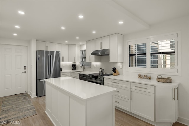 kitchen with tasteful backsplash, white cabinets, a center island, stainless steel appliances, and light wood-type flooring