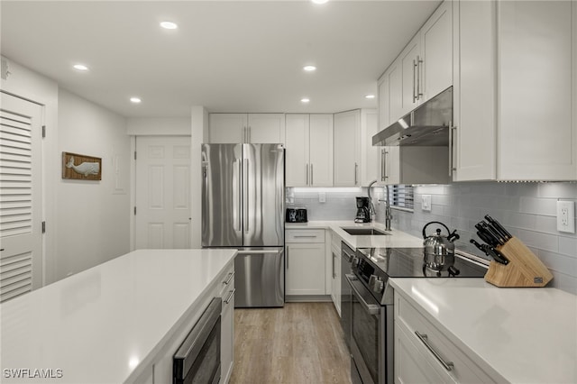 kitchen featuring stainless steel appliances, white cabinetry, sink, and light hardwood / wood-style floors