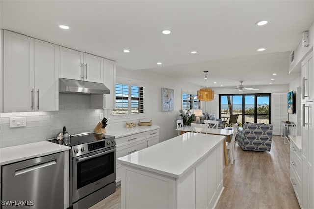 kitchen featuring stainless steel appliances, decorative light fixtures, a kitchen island, and white cabinets