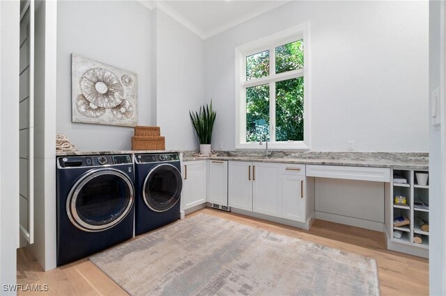 laundry room with sink, washing machine and dryer, cabinets, ornamental molding, and light hardwood / wood-style floors