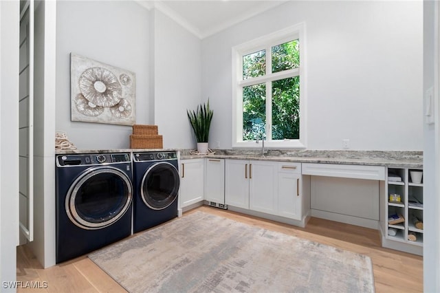 washroom featuring cabinet space, light wood-style flooring, crown molding, separate washer and dryer, and a sink