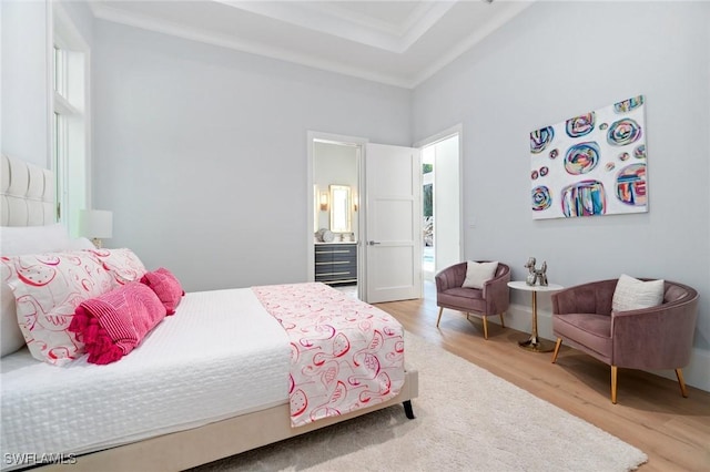 bedroom featuring hardwood / wood-style flooring, ornamental molding, and a raised ceiling