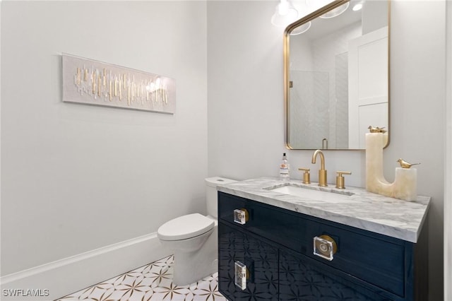 bathroom with toilet, baseboards, and vanity