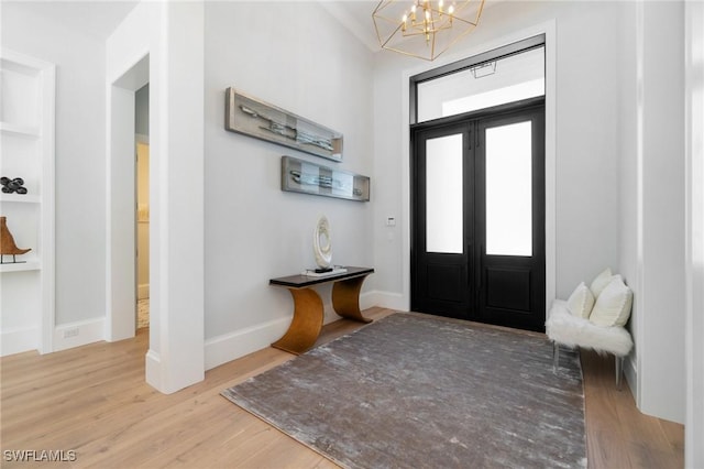 foyer featuring hardwood / wood-style floors, an inviting chandelier, and french doors