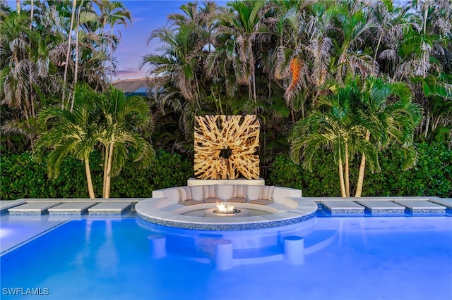 pool at dusk featuring a fire pit