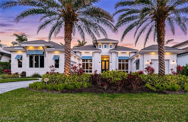 view of front of house featuring stucco siding, a front yard, and an attached garage