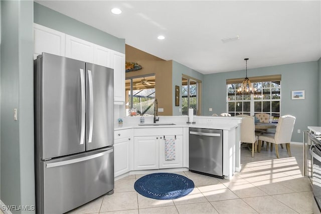 kitchen featuring sink, decorative light fixtures, light tile patterned floors, stainless steel appliances, and white cabinets