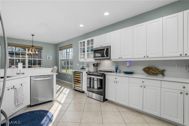 kitchen featuring stainless steel appliances, white cabinetry, pendant lighting, and wine cooler