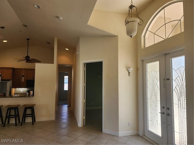 foyer entrance featuring light tile patterned floors, a healthy amount of sunlight, french doors, and high vaulted ceiling