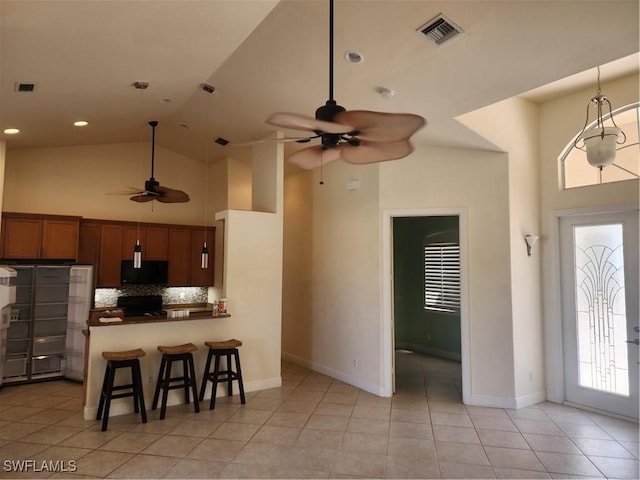 kitchen with stove, visible vents, high vaulted ceiling, and black microwave