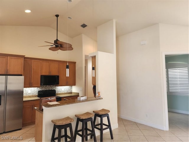 kitchen with a kitchen bar, brown cabinets, range with electric cooktop, black microwave, and stainless steel fridge with ice dispenser