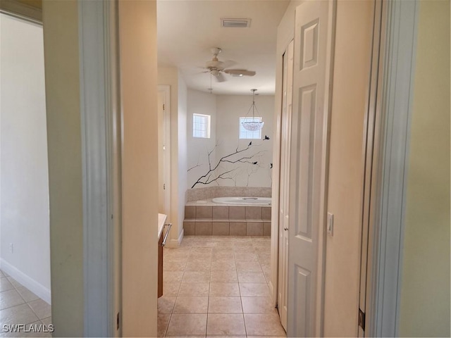 hall with light tile patterned flooring, visible vents, and baseboards