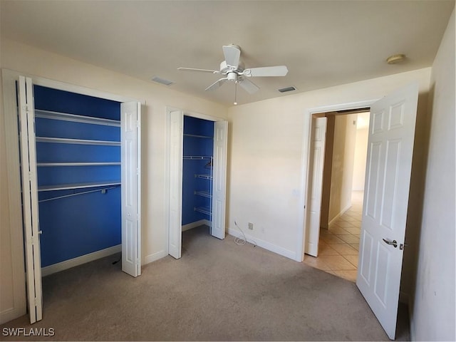 unfurnished bedroom with visible vents, two closets, ceiling fan, baseboards, and carpet