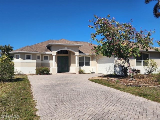 ranch-style home with decorative driveway, an attached garage, and stucco siding