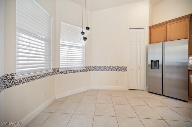 10347 Wood Ibis Ave, Bonita Springs, FL 34135 - kitchen with brown cabinetry, light tile patterned flooring, stainless steel fridge with ice dispenser, and baseboards